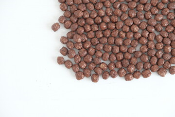 Chocolate corn balls scattered on a white background. Top view. Copy, empty space for text