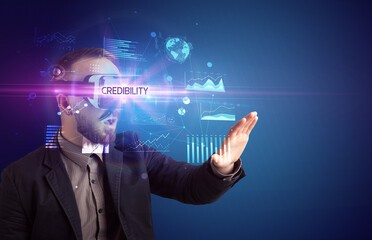 Businessman looking through Virtual Reality glasses with CREDIBILITY inscription, new business concept