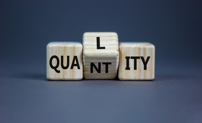 Quality over quantity symbol. Turned cubes and changed the word 'quantity' to 'quality'. Beautiful grey table, grey background, copy space. Business and quality over quantity concept.