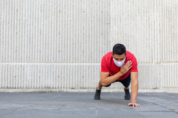 Mexican man doing push ups outdoors wearing a white face mask