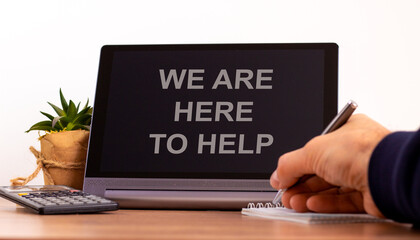 Fototapeta na wymiar Support symbol. Tablet with words 'we are here to help'. Online business and support during COVID-19 quarantine. Businessman hand with pen, house plant. Copy space. Support concept.