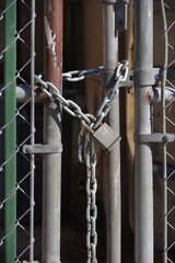 Close-up partial view of a fence gate secured with a chain and padlock