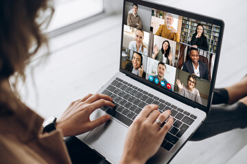 Fototapeta na wymiar Back view of female employee communicate on video call with multiracial colleagues, woman worker conducts webcam group conference with business partners uses laptop and app