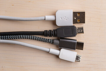 Mini USB, micro USB, and USB type-C connectors, with connecting cables, photographed closely. Evolution and change of USB connectors.