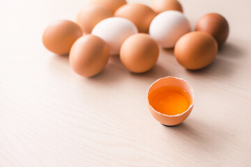 Half of a broken egg with a group of eggs on a background on a wooden table.