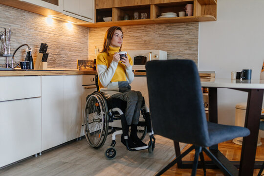 Woman sitting in her wheelchair and drinking coffee