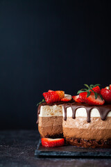 Three chocolates cake with chocolate drips on a black background. Layered cake with milk, black and...