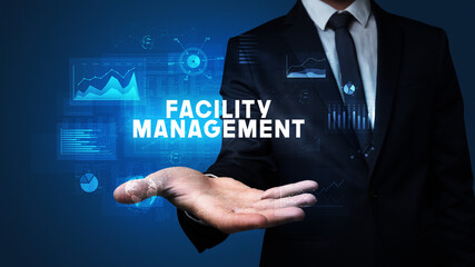 Hand of Businessman holding FACILITY MANAGEMENT inscription, business success concept