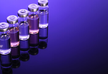 Glass vials with liquid without label on a dark blue background, coronovirus vaccine, Vaccination against the virus and the flu, vaccination, vaccine clinical trials,  Pharmacy, Medical Research