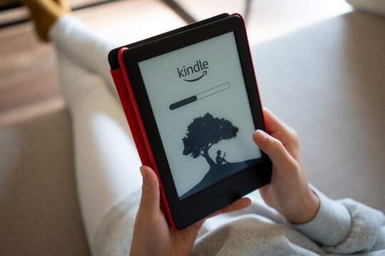Portland, OR, USA - Feb 20, 2021: A girl opens her kindle to read ebooks at home.