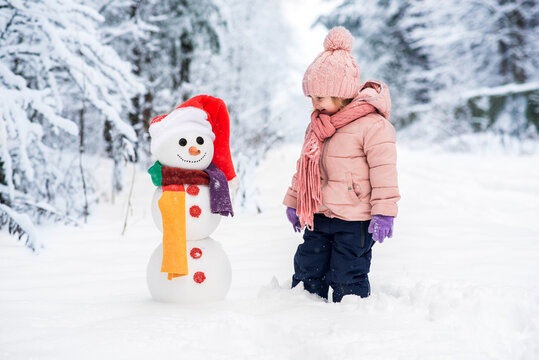 Cute boy and girl building snowman in winter forest