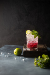 Refreshing cocktail with berry syrup or liqueur,tonic,crushed ice,fresh mint and lime on dark background.Copy space.