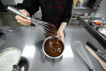 The pastry chef mixes the chocolate ganache with a whisk.