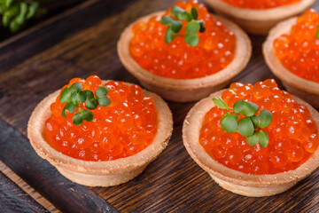 Delicious fresh red caviar on a dark concrete table