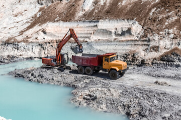 The excavator is extracting a watered layer of minerals in a clay quarry.