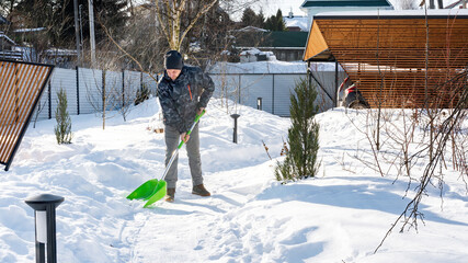 The consequences of heavy snowfall in the courtyard. A man cleans snow from the tracks with a large...