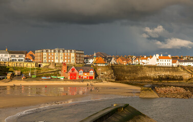 Cullercoats Bay bathed in sunshine just as before dark rain clouds loom above