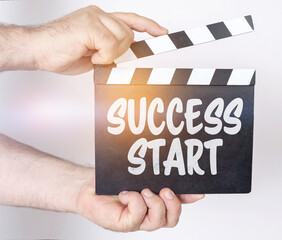 On a white background, a man holds a clapperboard in his hands on which it is written - SUCCESS...