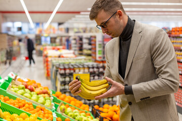 A businessman is buying fruits in the supermarket.