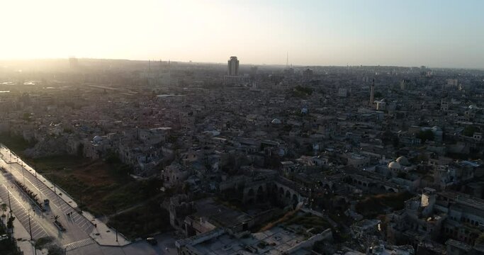 Aerial view above a syrian city under the sunrise. We can see the city of Aleppo all over the horizon 4K