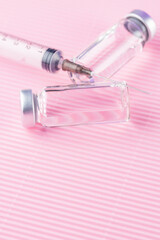 Healthcare cure concept with vaccine and syringe injection. Vaccines and syringe on a pink background for prevention and immunization. Copy space. Top view