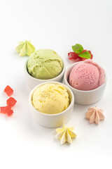 Strawberry, pistachio and lemon ice cream balls in a bowl, isolated on a white background.