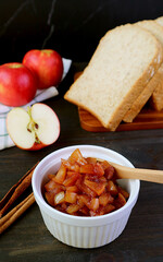 Bowl of homemade apple compote with wholemeal bread and fresh apples in the backdrop