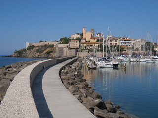 Fototapeta na wymiar Panorama of the fortified medieval village of Talamone from the walkway along the pier with the boats moored in the port
