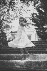 happy child dancing outdoors free in stairs with long hair blowing in the wind in sunny summer day