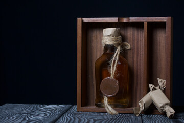 Gift alcohol. A bottle of alcohol and candy are in a wooden box.