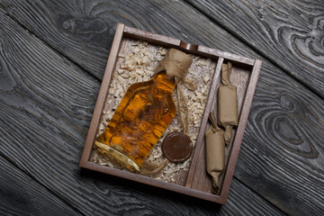 Gift alcohol. A bottle of alcohol and candy are in a wooden box. On wood sawdust.