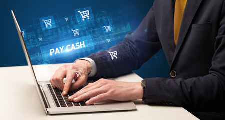 Businessman working on laptop with PAY CASH inscription, online shopping concept