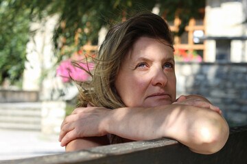 Portrait of the beautiful woman with crossed arms leaning on the bench back 