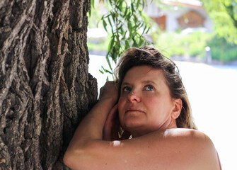 Portrait of a beautiful woman leaning against the tree trunk