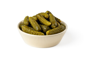Pickled gherkins in a beige ceramic bowl isolated on a white background. Whole green cornichons marinated with dill, garlic and mustard seeds. Crunchy baby pickles. Tasty canned vegetables.