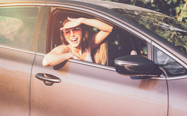 Naklejka premium Portrait of pretty smiling woman in car window. Concept traveler tourist trip by avtomobil.