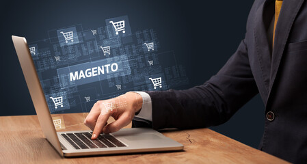 Businessman working on laptop with MAGENTO inscription, online shopping concept
