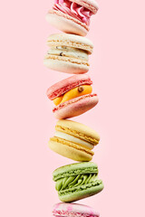 Pile of different types sweet and colorful french macarons on pink background. Food mockup for the holiday invitation card.