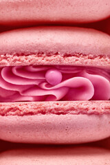 Macro plan of pink French macaroons captured as shells with a pearl. Close up of the cream filling with different toppings and fluffy cookies.