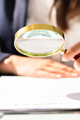 Businesswoman Looking At Contract Form Through Magnifying Glass