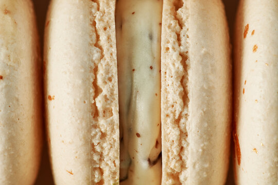 Macro plan of French macaroons. Close up of the cream filling with different toppings and fluffy cookies.
