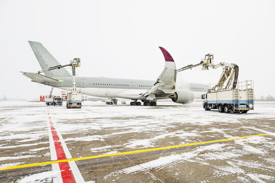Winter at the airport. Snow storm. Airplane de-icing before take off. De-icing the aircraft before the flight. The de-icing machine sprinkles the wing of a passenger plane with de-icing fluid.