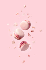 French macarons flying in the air among the crumbs on pink background. Levitation concept. food...