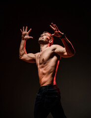 Handsome sexy man with athletic shirtless body showing muscle standing isolated on black background. Sport, bodybuilding motivation. Narcissism and masculinity. Dark studio shot copy space portrait