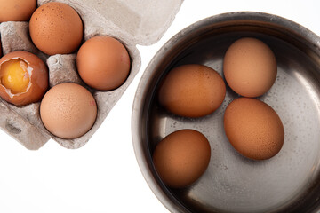 Top view of raw chicken eggs in saucepan on white background