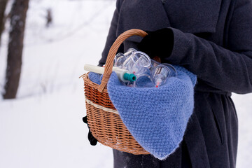 A woman in a gray coat holds a basket of hijama cans. Hijama jars and hijama pump, bloodletting, Chinese medicine
