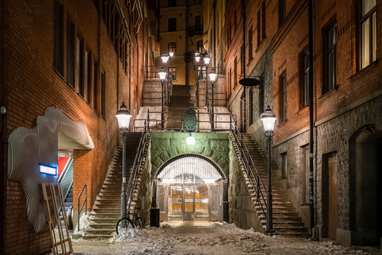 Beautiful night scene of stone steps  with bright lamp posts and vintage old red brick building over pedestrian underground tunnel entrance in Stockholm Sweden.