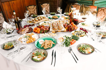 Fototapeta premium The feast of the round table full of delicious food and snacks, a beautiful setting, catering, holiday in the fresh air