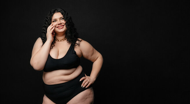 Plus Size Model In Lingerie, Fat Sexy Woman In Underwear On Black Studio Background, Body Positive Concept, Full Length Portrait. Girl Model Plus Size Talking On The Phone