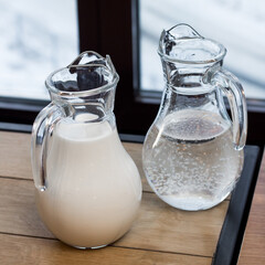 Two jugs. One with water and one with milk. Pitchers on the table
